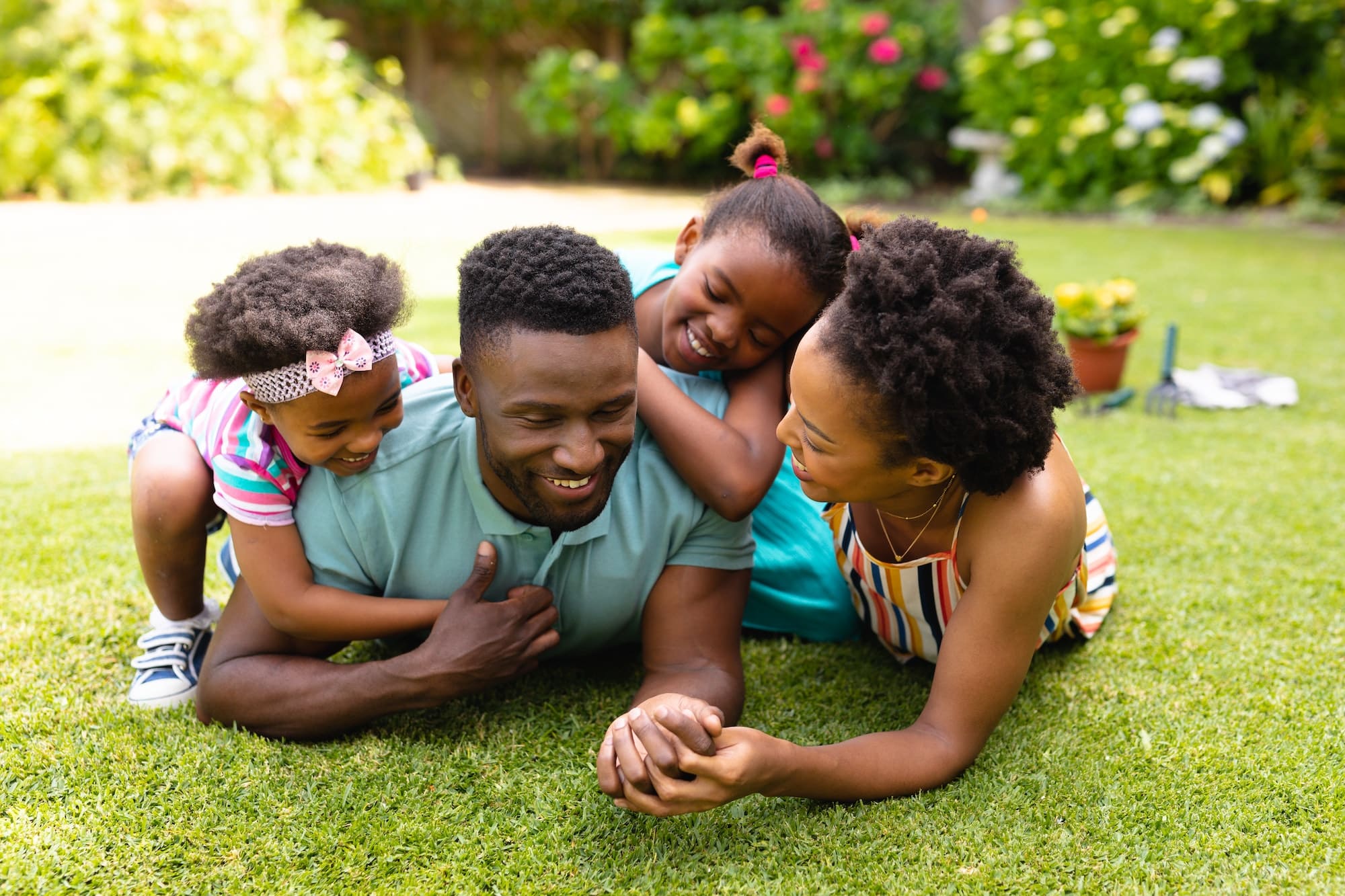 Happy african american family lying on grass at backyard garden