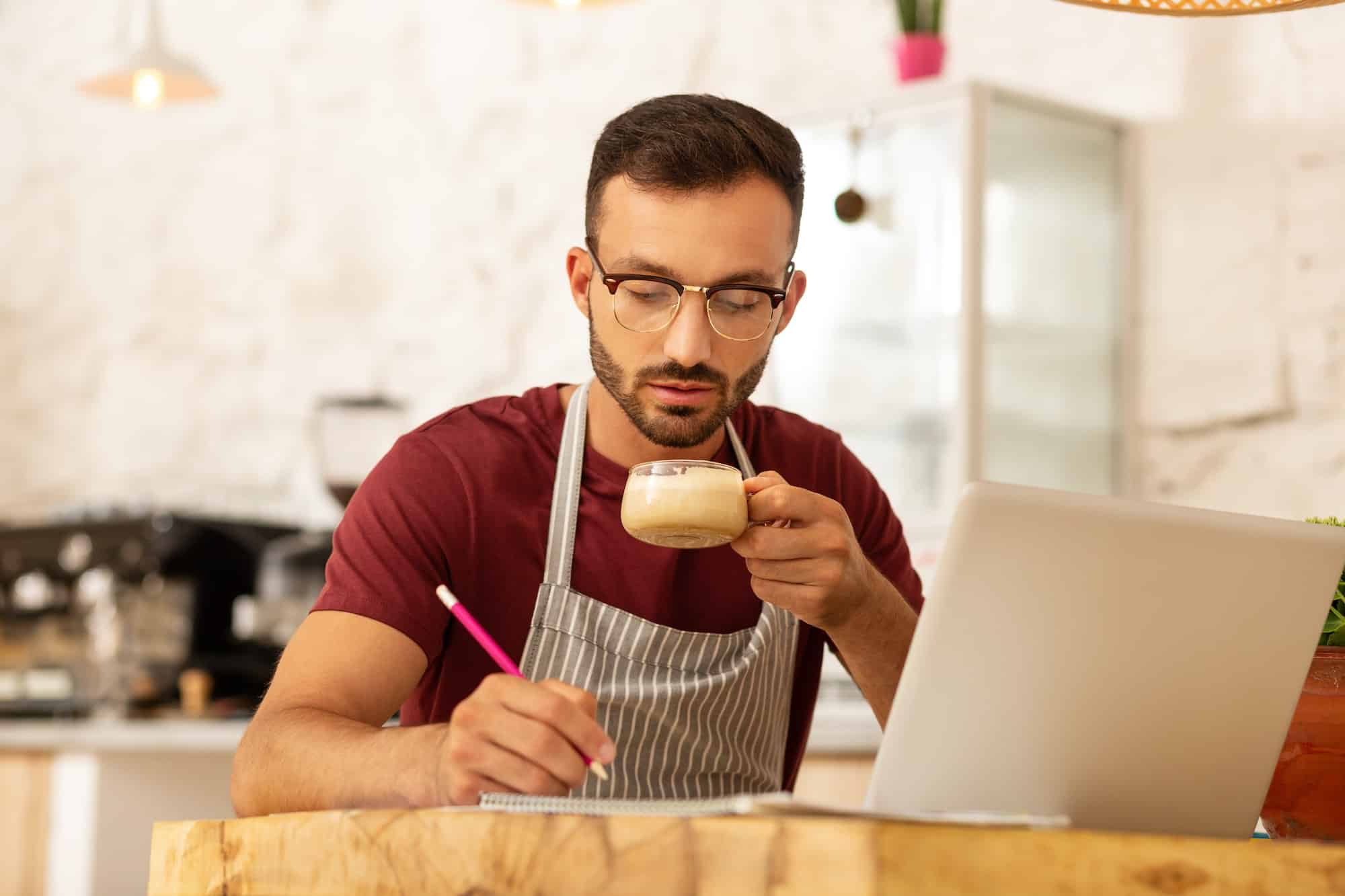 Un homme d'affaires occupé boit du cappuccino et travaille